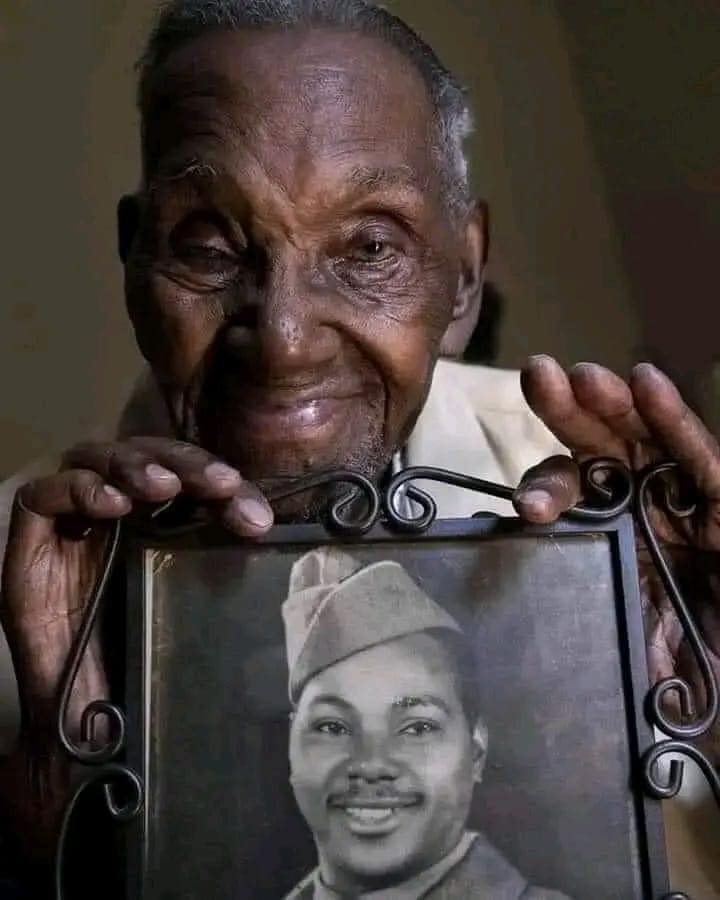 Oldest WWII veteran aged 110 holding a photo of himself